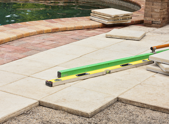 This image shows pavers being placed on a pool deck.