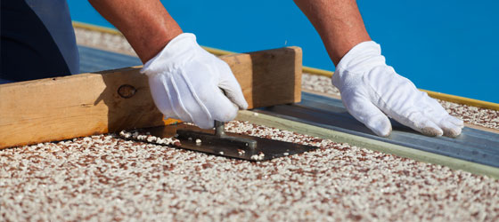 This image shows a man resurfacing a pool deck.
