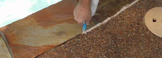 This image shows a man resurfacing a pool deck area.