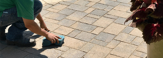 resealing This image shows a man cleaning pavers.