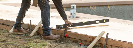 This image shows a man resurfacing a pool deck area.