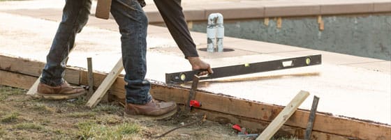 8 Emergency Repairs This image shows a man resurfacing a pool deck area.