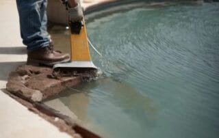 This image shows a man repairing craks on the pool deck.